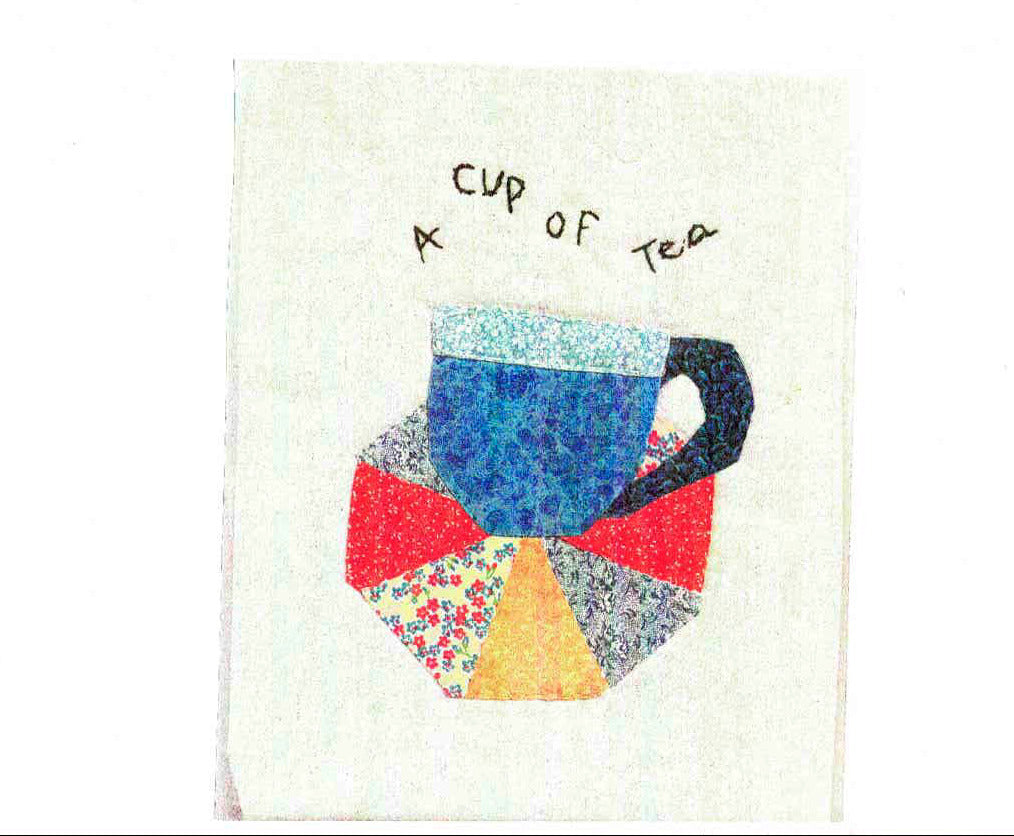 Front of a white card with the artists quilted picture of a cup of tea with the text "A cup of tea"