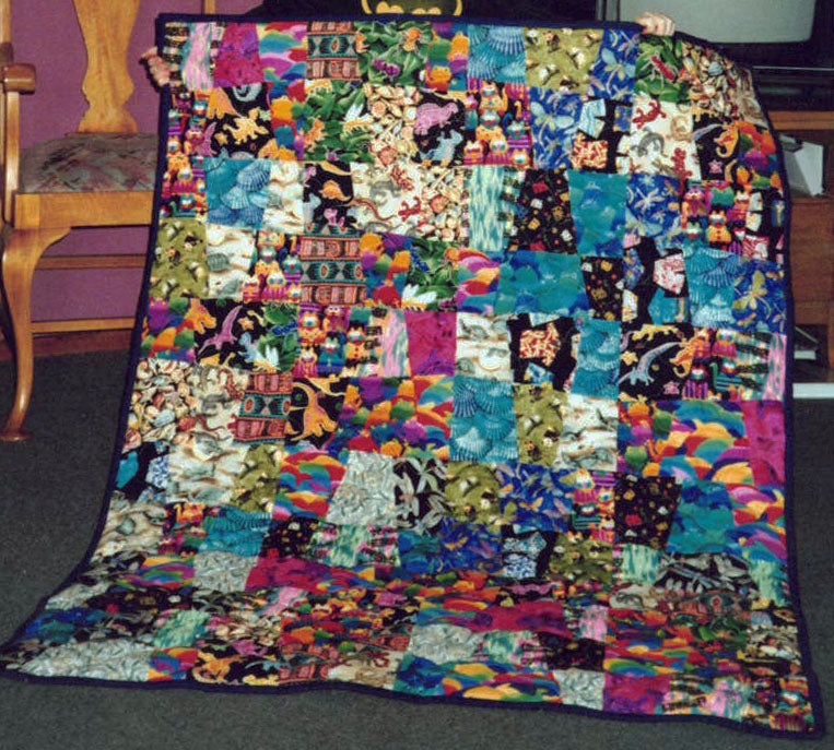 A photograph of a busy, fun, wonkily designed quilt with a black border.