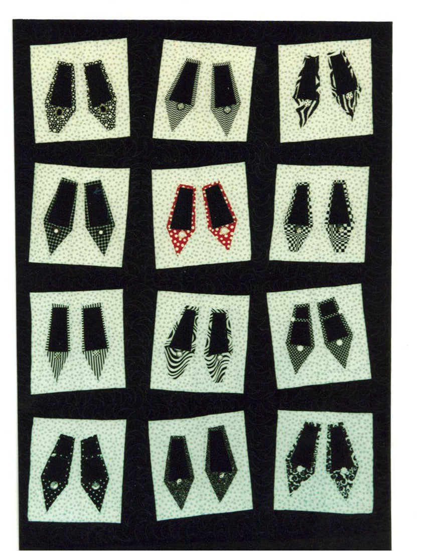 A black and white quilt with wonky blocks of shoes in various patterns. One pair is red.