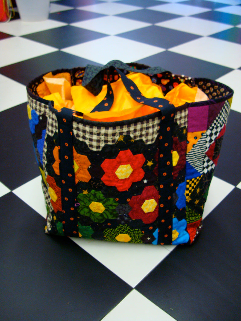 Colorful fabric shopping bag with floral quilting patterns on a checkered floor
