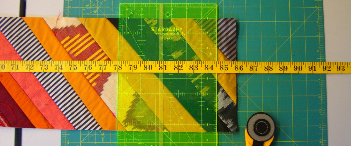 Colorful fabric squares on a cutting mat with a ruler and rotary cutter.