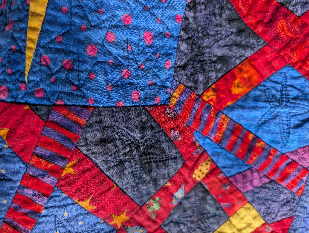 Colorful quilt with star patterns in blue, red, and yellow.