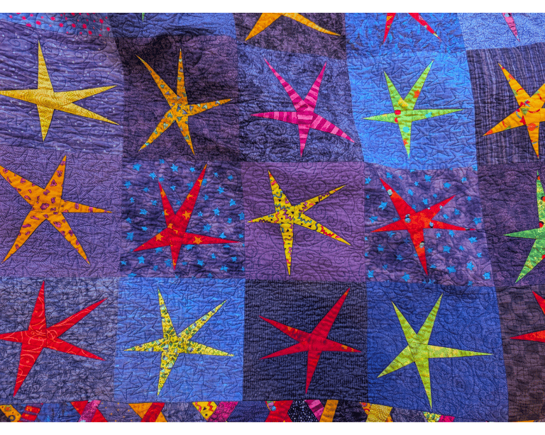Colorful star-patterned quilt with a blue background