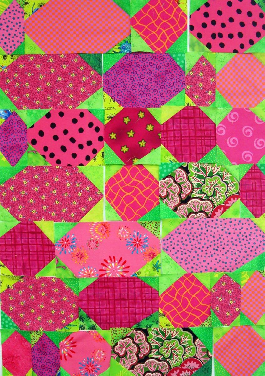 Colorful quilt before being stitched with various patterns on a green background