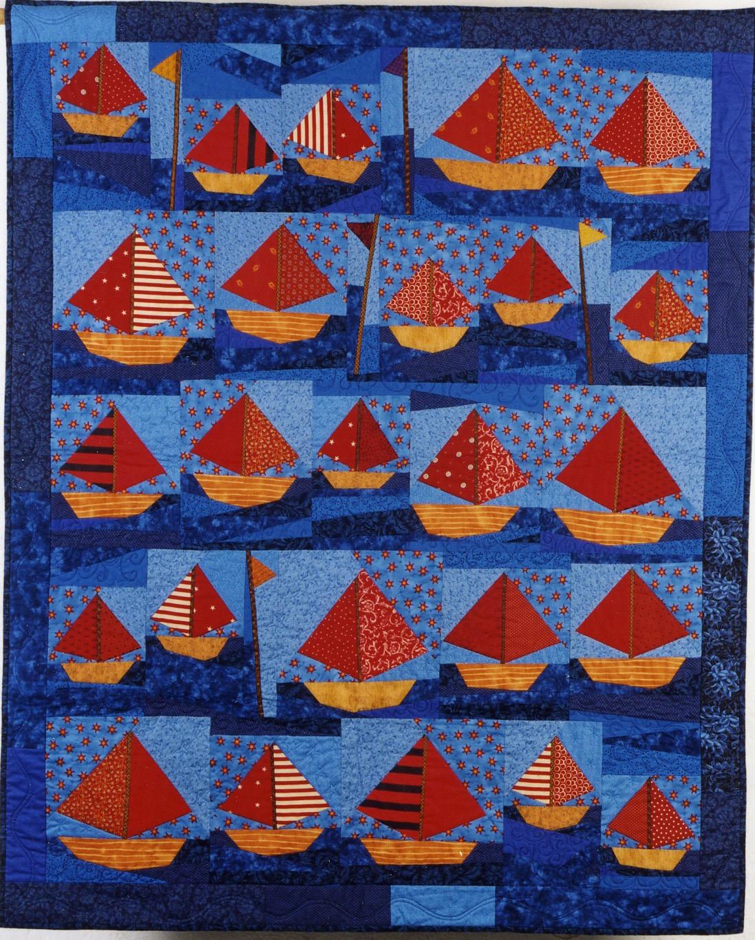 Quilt with red and orange sailboats on a blue background