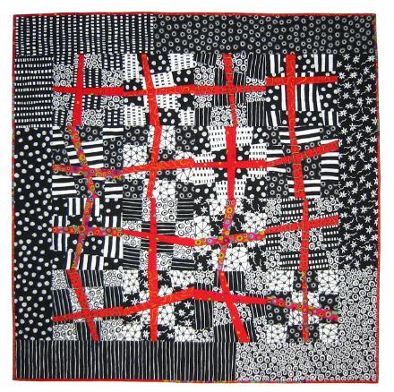 Abstract quilt with black, white, and red patterns on a black background